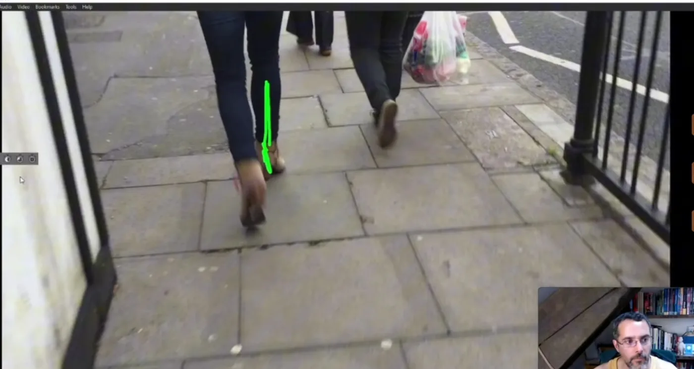 Gros plan sur les jambes d'une personne qui marche sur un trottoir, avec un trait vert qui souligne l'axe de la cheville et l'appui du pied